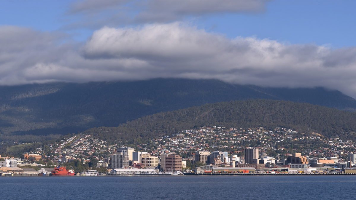 Hobart's waterfront and city centre below a cloud-covered kunanyi / Mount Wellington